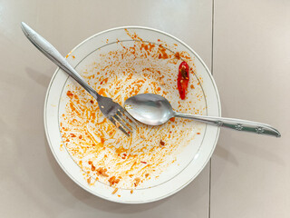 Empty dish with food remnants and utensils.