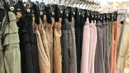 A variety of pants displayed on hangers in a retail store.