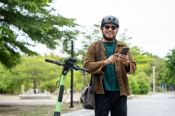 Young Asian man rent the scooter EV scan by smartphone. Sustainable save energy lifestyle. Commute and carbon neutral transportation. Asian tourist man put on helmet ride the scooter EV