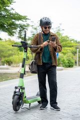 Young Asian man rent the scooter EV scan by smartphone. Sustainable save energy lifestyle. Commute and carbon neutral transportation. Asian tourist man put on helmet ride the scooter EV