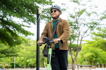 Young Asian man ride scooter EV eco friendly transport. Sustainable save energy lifestyle. Commute and carbon neutral transportation. Asian tourist man put on helmet ride the scooter EV