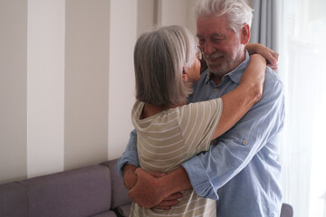 Senior couple in their 70s sharing loving and tender moments at home. A heartwarming scene of...