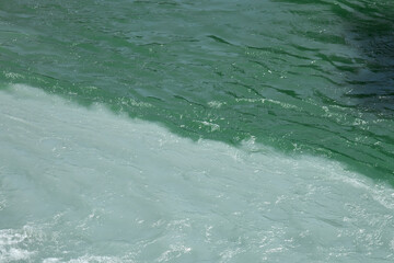 confluence of two rivers of different colors, emerald green and turquoise muddy water, riverside....