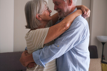 Senior couple in their 70s sharing loving and tender moments at home. A heartwarming scene of...
