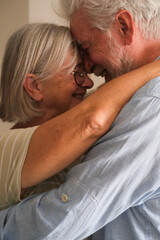 Senior couple in their 70s sharing loving and tender moments at home. A heartwarming scene of...