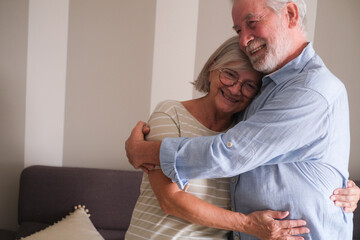Senior couple in their 70s sharing loving and tender moments at home. A heartwarming scene of...