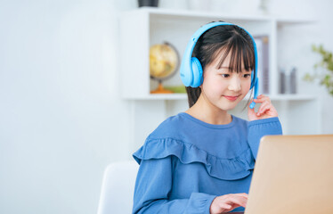 ヘッドホンをつけてノートパソコンで勉強する女の子