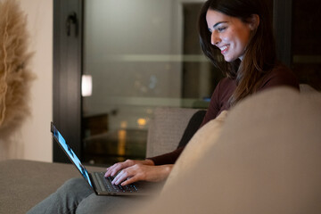Young woman alone at home working late at night on her laptop. Freelancing, studying, chatting...