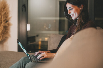 Young woman alone at home working late at night on her laptop. Freelancing, studying, chatting...