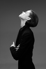black and white woman with short hair standing sideways with crossed arms, wearing dark clothing...