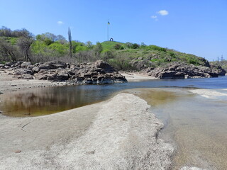 Landscape from the Dnieper rapids to the rocky coast of Khortytsia against the background of a sunny blue sky.