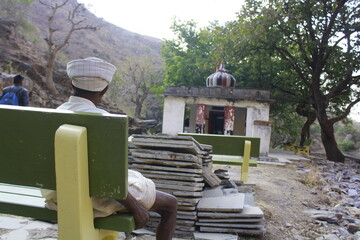 old man sitting near a temple in the nature