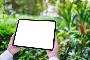 Mockup image of a woman holding digital tablet with blank white desktop screen in the nature outdoors