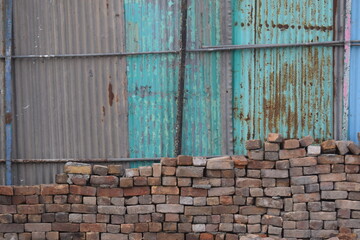 blue sky with wall A bricks stone with blue corrugated iron metal fence / Zinc wall,  traditional grungy door of Indian village house, stack of bricks close up