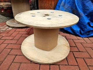 Outdoor wooden cable reel on textured surface used in packaging and heavy-duty wiring storage...
