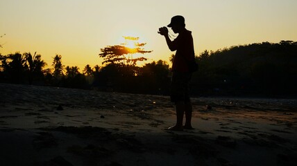 Silhouette of a photographer capturing sunset by the beach, evoking creativity, freedom, and...