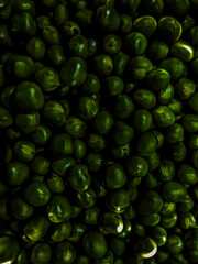 A close-up of freshly picked green peas in an altered dark green colour.