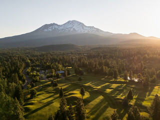 Amazing  panoramic view of a golf course in the summer morning sun, with long shadows, under Mount...