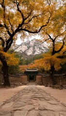 Autumn path through a temple garden, with mountains in the background.  Golden leaves frame a stone pathway leading to a traditional Asian temple gate