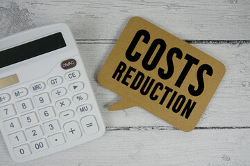 Costs Reduction text with calculator on wooden background