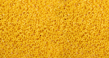 Raw yellow cavatappi pasta texture background top view. Pile of dry uncooked noodles pattern