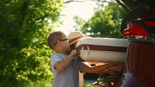 Journey of two cute boy and girl happy to spend holidays outdoor in nature. Kids are leaving and load suitcases for long distance road trip. Little brother and sister preparing to rest in summertime.