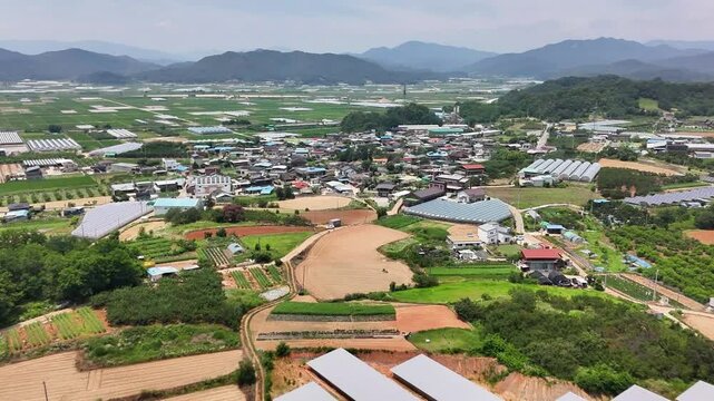 This is a drone image taken on July 3, 2025 in Ujeong, Apo-eup, Gimcheon-si, Korea. It shows greenhouses, agricultural facilities, rural roads, and farmland against the backdrop of a rural village.