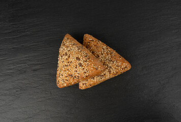Triangular bun closeup. Wheat bread with sesame and flax seeds, healthy whole grain bakery