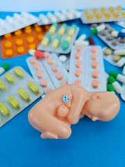 A plastic baby figurine is positioned at the center, cradled in a fetal position concept