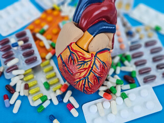 Heart model surrounded by a variety of colorful pills and capsules