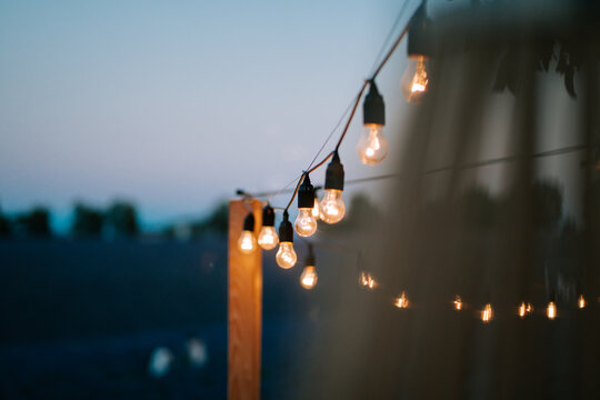 Outdoor string lights illuminate a tranquil evening sky at a festive gathering spot