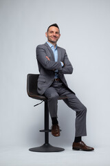 Professional Man in Gray Suit Sitting on Stool with Arms Crossed