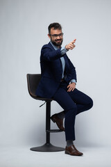 Spanish Businessman in Suit Sitting and Pointing Off Camera