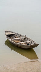 Obraz premium Serene Waters Awaits An Old Wooden Rowboat Gently Floating on Calm Water Reflecting the Sky A Peaceful Scene of Tranquility and Stillness on the Lake