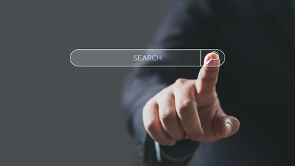 A close-up of a hand pointing at a search bar, symbolizing digital exploration and online searching.