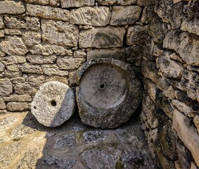 Two stone objects are sitting on a stone floor. One of them is a large round stone with a hole in...