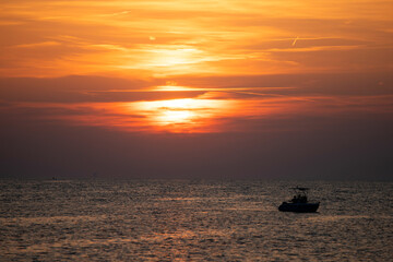 Boat silhoutted against the orange sky