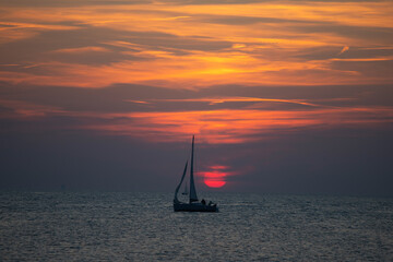 Sailing boat silhoutted against the orange sky