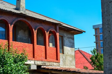 A red brick building with a red roof and a chimney. The building is empty and has a lot of windows