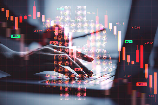 Digital bitcoin symbol overlaying hands typing on laptop with red financial chart bars showing market crash and cryptocurrency price collapse.