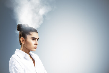 Businesswoman under stress with steam rising from head symbolizing burnout and overwork in...