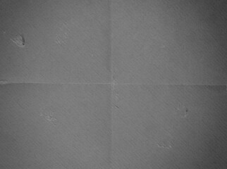 A high-resolution close-up of a grey paper surface showing subtle horizontal and vertical fold...