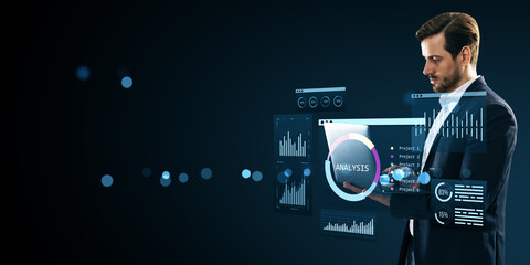 Businessman interacting with futuristic holographic analysis dashboard displaying data charts and financial infographics on dark background.