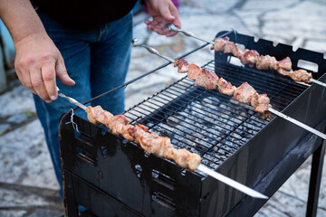 Person Barbecuing Skewers on a Grill Outdoors with Meat