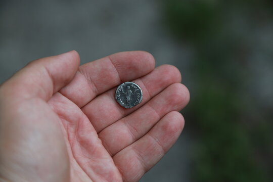 Antique silver coin of ancient Rome in hand - Powered by Adobe