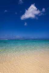 Idyllic crystal clear azure blue ocean water covering a shallow tropical reef under a deep blue sky. Captured from the idyllic sandy shoreline.