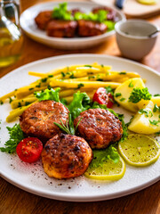 Fried chicken meatballs with boiled potatoes and wax beans on wooden table	