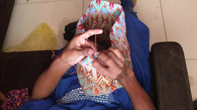 Hands of a Wayuu woman from La Guajira, North Colombia, skillfully weave a traditional Wayuu mochila. Bright colorful patterns reflect the tribe&rsquo;s cultural artistry-  iconic Colombian folk handicraft.