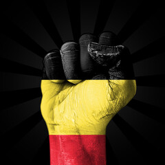 Belgium's flag painted on fist on the dark backdrop, freedom, and independence