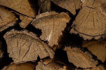 Pile of split firewood, ready for burning. Close-up of weathered wooden planks showing knots and...
